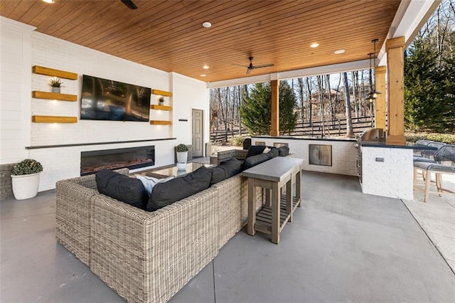 view of patio with area for grilling, an outdoor living space with a fireplace, ceiling fan, and an outdoor kitchen