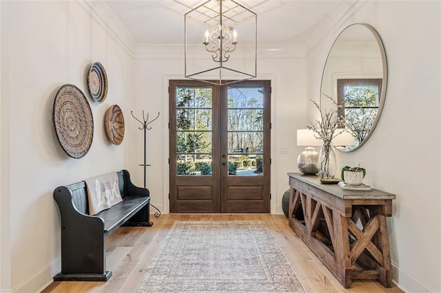 doorway featuring crown molding, light hardwood / wood-style floors, french doors, and a notable chandelier