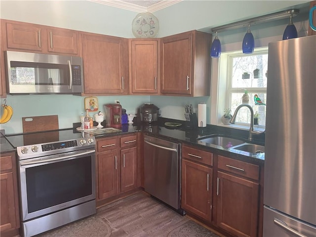 kitchen featuring crown molding, dark stone countertops, a sink, stainless steel appliances, and dark wood-style floors