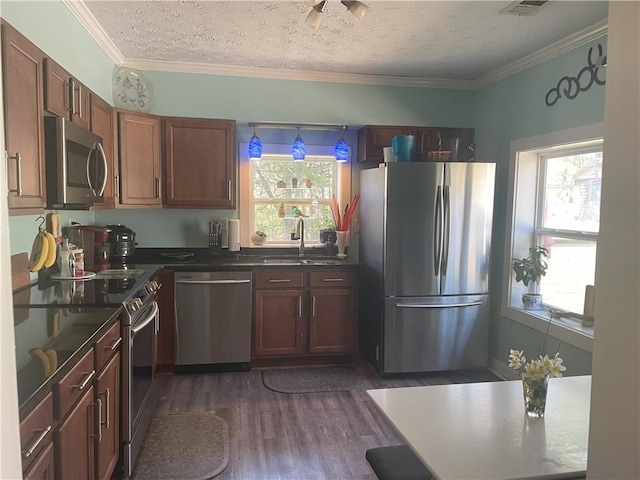 kitchen featuring dark wood-type flooring, crown molding, appliances with stainless steel finishes, and a sink