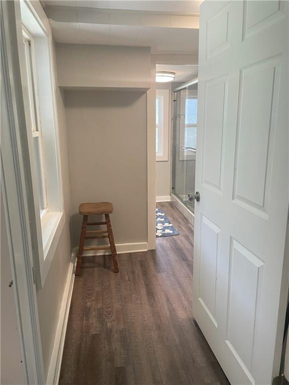 corridor featuring baseboards and dark wood-style floors