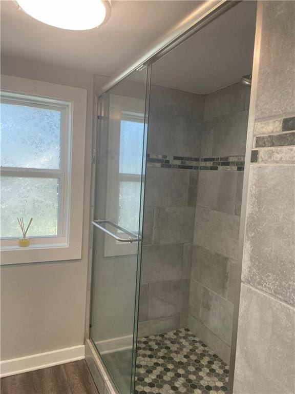 bathroom with baseboards, a shower stall, and wood finished floors