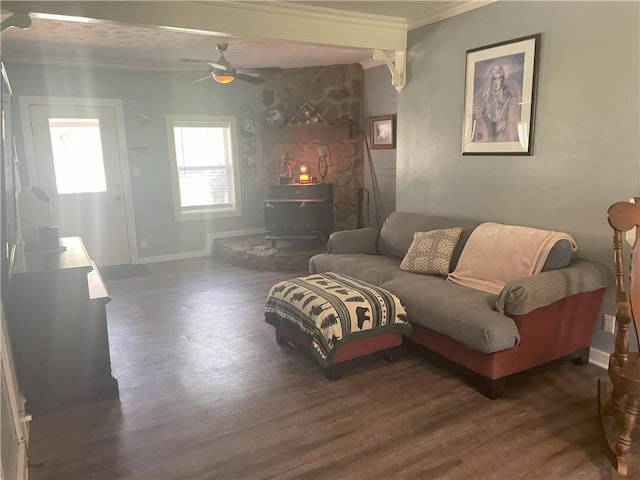 living room featuring crown molding, a wood stove, wood finished floors, and baseboards