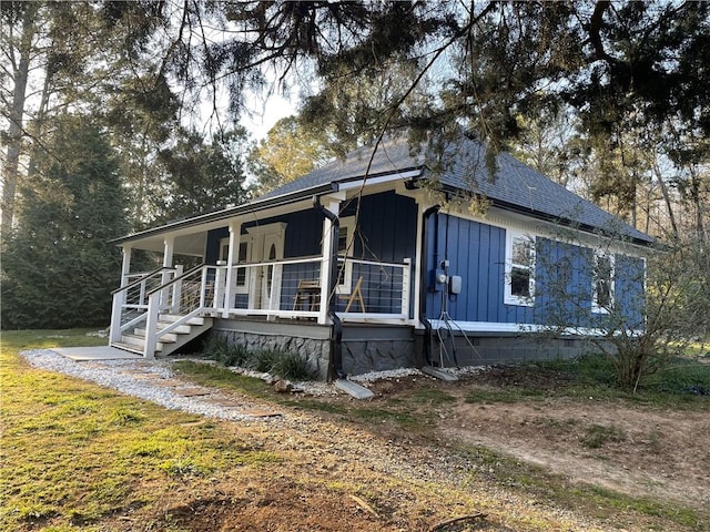 view of front facade with roof with shingles, crawl space, and covered porch