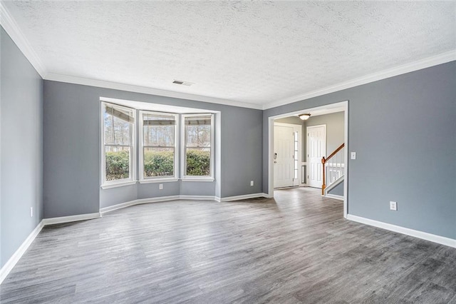 spare room featuring wood-type flooring, a textured ceiling, and crown molding