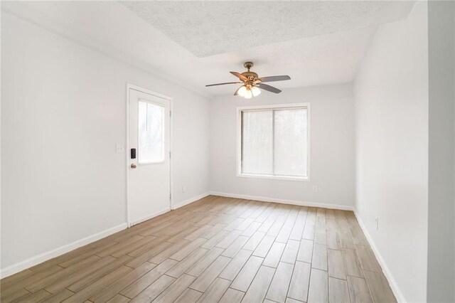 spare room featuring light wood-type flooring, a wealth of natural light, and baseboards