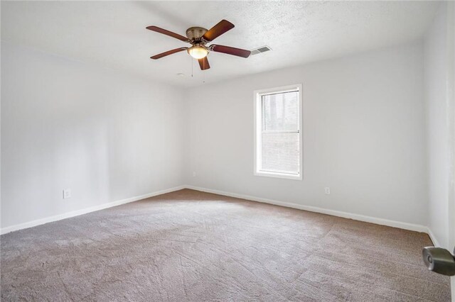 carpeted spare room featuring baseboards, visible vents, ceiling fan, and a textured ceiling