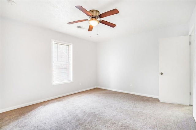 empty room featuring carpet floors, ceiling fan, visible vents, and baseboards