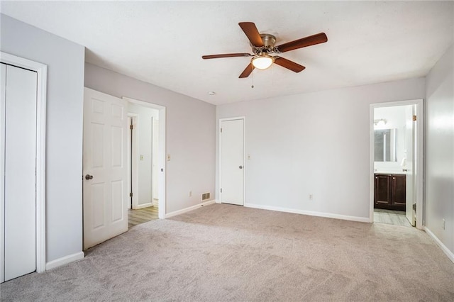 unfurnished bedroom with light carpet, visible vents, baseboards, ensuite bath, and ceiling fan