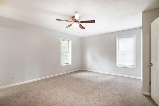 empty room featuring carpet floors, a textured ceiling, baseboards, and a ceiling fan