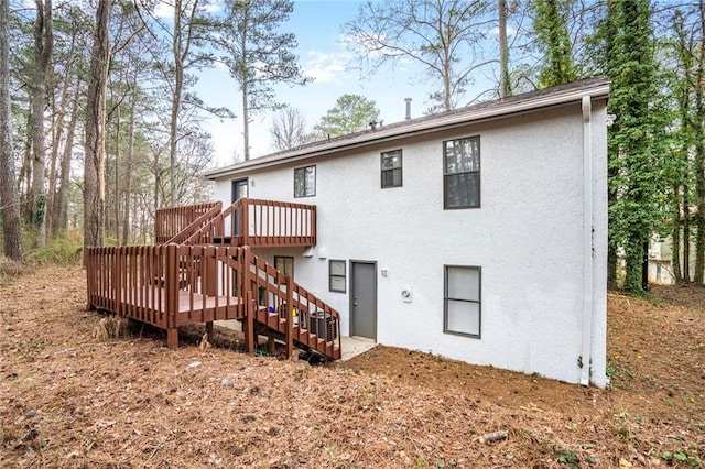 rear view of property with a deck, stairs, and stucco siding