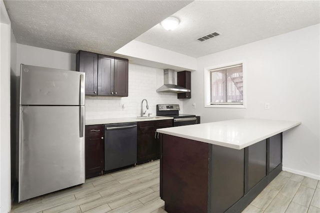 kitchen with visible vents, decorative backsplash, stainless steel appliances, wall chimney range hood, and a sink