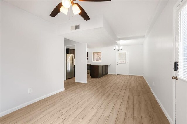 unfurnished living room featuring light wood-type flooring, baseboards, visible vents, and ceiling fan with notable chandelier