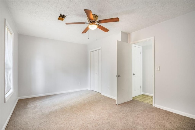 unfurnished bedroom featuring carpet, a closet, a textured ceiling, and baseboards