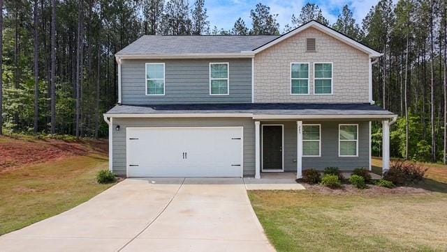traditional home featuring covered porch, an attached garage, concrete driveway, and a front yard