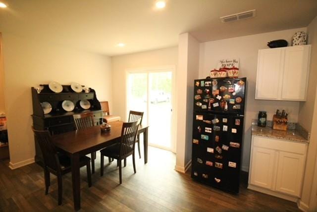 dining room with recessed lighting, baseboards, dark wood-type flooring, visible vents, and a bar