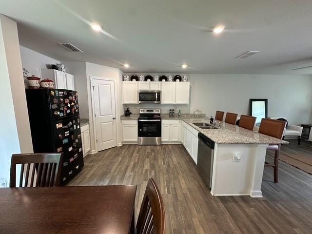 kitchen featuring visible vents, dark wood-style flooring, a breakfast bar, and stainless steel appliances