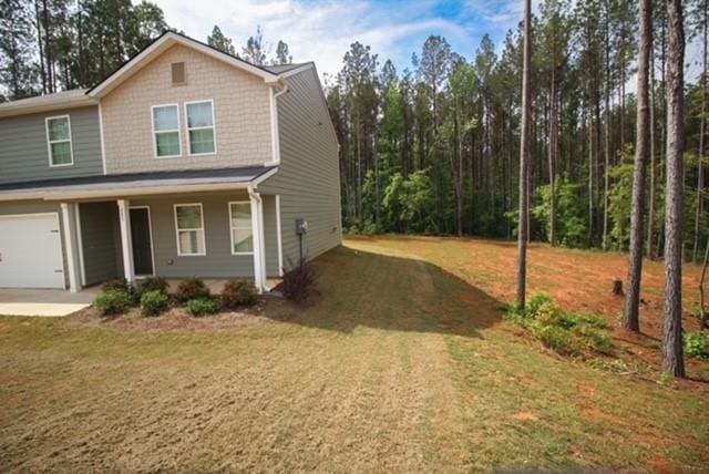 exterior space with a porch, an attached garage, and a front yard