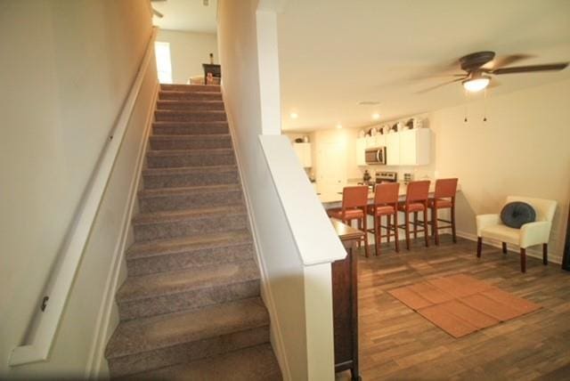 stairway with baseboards, a ceiling fan, and wood finished floors