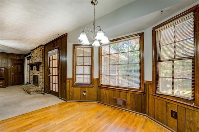 unfurnished dining area featuring a fireplace, a healthy amount of sunlight, and light hardwood / wood-style flooring