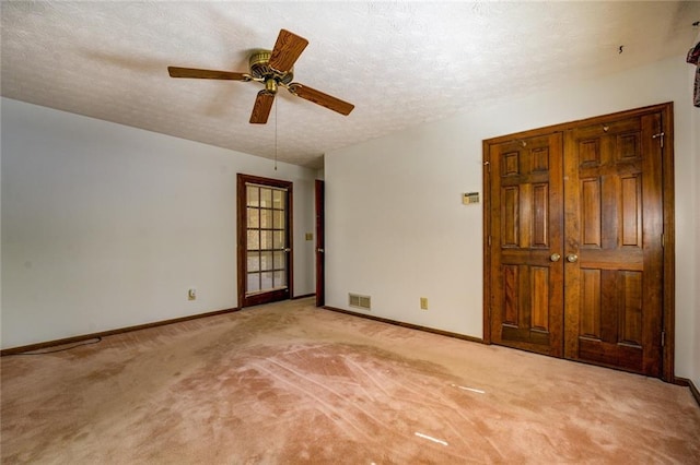 unfurnished room featuring ceiling fan, light colored carpet, and a textured ceiling