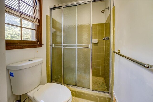 bathroom featuring toilet, tile patterned floors, and a shower with shower door