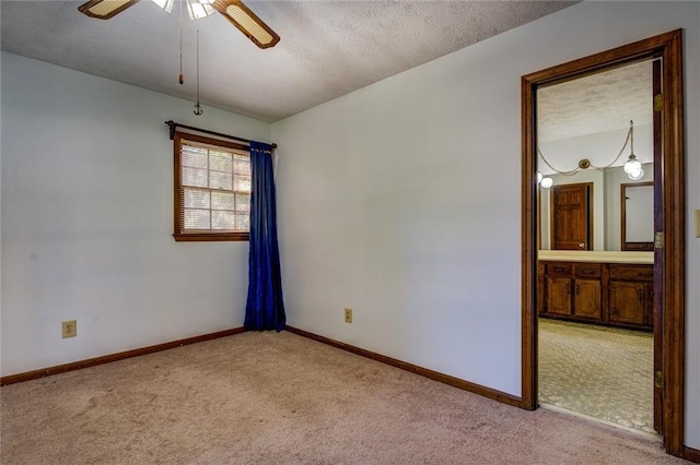 empty room featuring a textured ceiling, light carpet, and ceiling fan