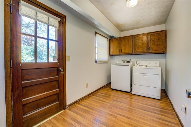 laundry room featuring cabinets, a textured ceiling, washer and dryer, and light hardwood / wood-style floors