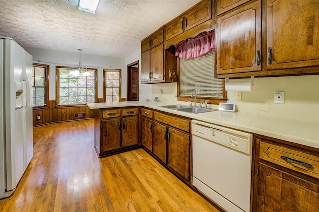 kitchen with light hardwood / wood-style floors, kitchen peninsula, a textured ceiling, hanging light fixtures, and white appliances