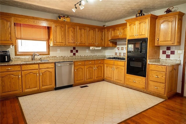 kitchen with sink, tasteful backsplash, light hardwood / wood-style floors, a textured ceiling, and black appliances