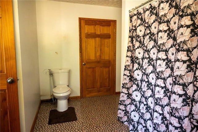 bathroom featuring tile patterned flooring, toilet, and a textured ceiling