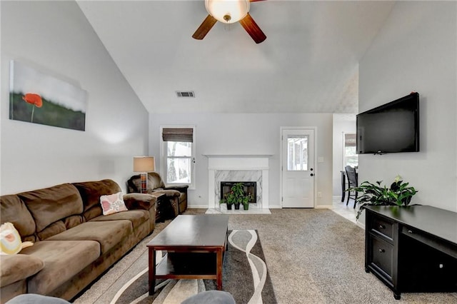 living room with light carpet, a premium fireplace, a healthy amount of sunlight, and ceiling fan