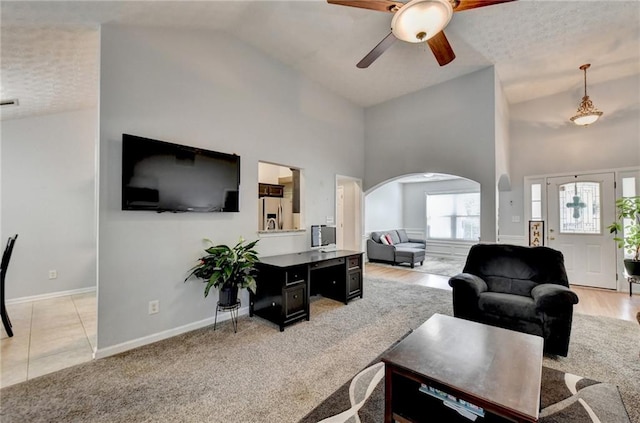 living room with light hardwood / wood-style floors, high vaulted ceiling, a textured ceiling, and ceiling fan