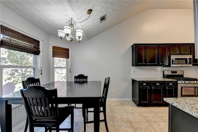 dining room with light tile patterned flooring, a textured ceiling, lofted ceiling, and a chandelier