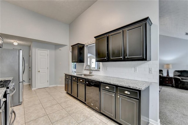 kitchen with lofted ceiling, light stone counters, light tile patterned floors, appliances with stainless steel finishes, and sink