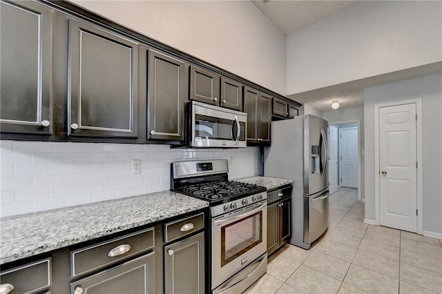 kitchen with appliances with stainless steel finishes, dark brown cabinetry, backsplash, and light tile patterned flooring