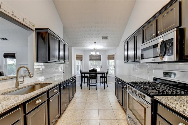 kitchen featuring lofted ceiling, hanging light fixtures, light tile patterned floors, sink, and stainless steel appliances