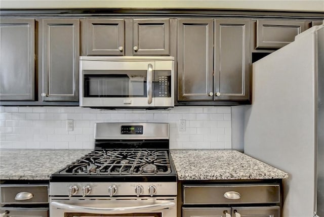 kitchen featuring light stone countertops, appliances with stainless steel finishes, backsplash, and dark brown cabinets