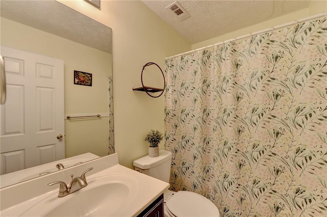 bathroom featuring vanity, a textured ceiling, toilet, and walk in shower