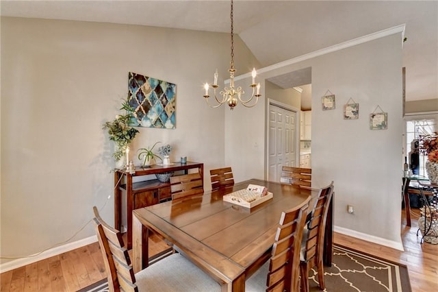 dining area with lofted ceiling, a notable chandelier, baseboards, and wood finished floors