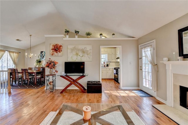 living room with vaulted ceiling, light wood finished floors, and a premium fireplace