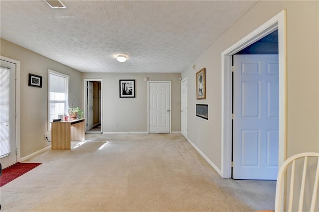 entrance foyer featuring light carpet, baseboards, visible vents, and a textured ceiling