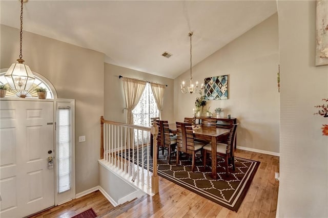 dining area featuring vaulted ceiling, wood-type flooring, visible vents, and an inviting chandelier