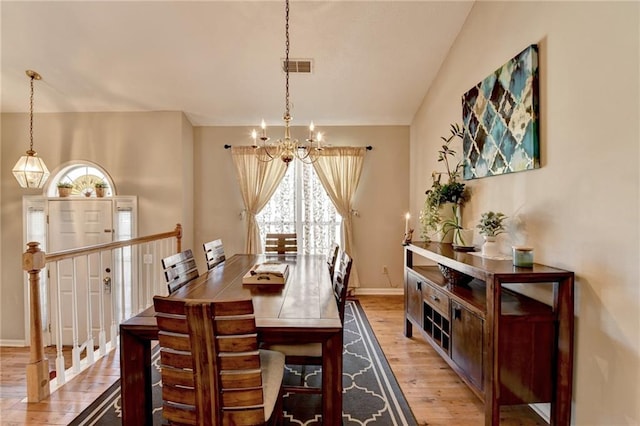 dining area featuring a notable chandelier, lofted ceiling, visible vents, light wood-type flooring, and baseboards