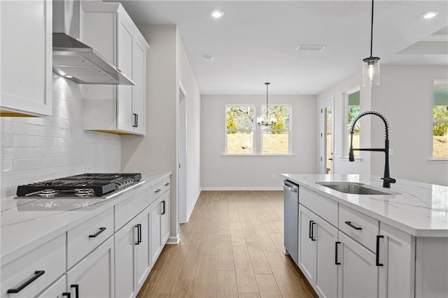 kitchen with wall chimney range hood, decorative backsplash, a sink, and plenty of natural light