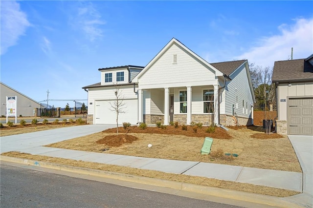 view of front of home with driveway, a porch, and stone siding