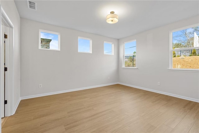 unfurnished room with baseboards, visible vents, light wood-type flooring, and plenty of natural light