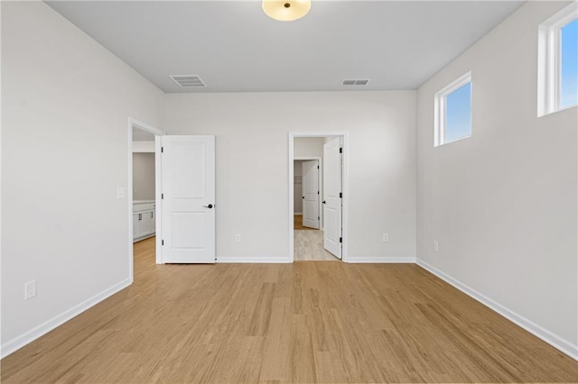 unfurnished bedroom featuring a spacious closet, baseboards, visible vents, and light wood-style floors