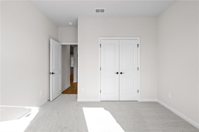 unfurnished bedroom featuring carpet flooring, baseboards, a closet, and visible vents
