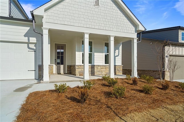 back of property with concrete driveway, a porch, and a garage